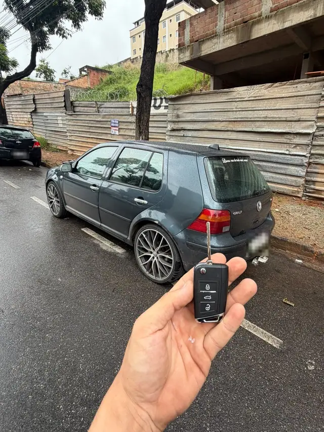 Chave canivete na mão, com a traseira de um VW Golf cinza ao fundo