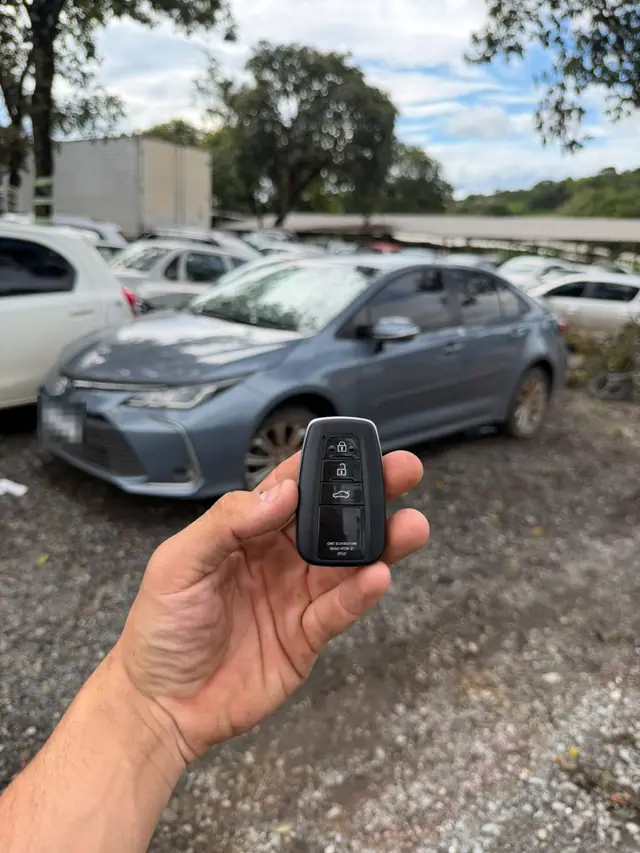 Chave de presença na mão, com um Toyota Corolla azul ao fundo